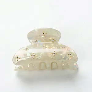Iridescent cream hair claw clip with sparkling rhinestones and gold studs on a 6cm frame
