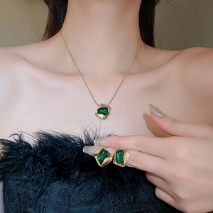 Model wearing vintage gold rhombic necklace and earrings set with green gemstones