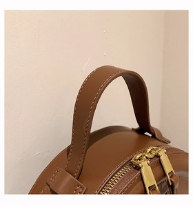 Details einer braunen Ledertasche mit goldenen Reißverschlüssen und Tragegriffen