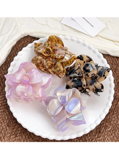 Detailed close-up of four floral acetate hair claws in pearlescent finishes and colors