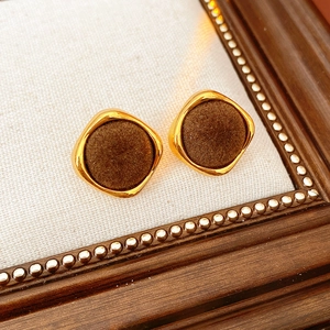 Gros plan sur des boucles d'oreilles carrées vintage avec bord doré et texture floquée
