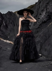 Close-up of black sequined corset dress with vibrant red feather waist accents