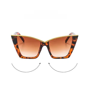 Detail of tortoiseshell cat-eye sunglasses with gold metal trim and brown gradient lenses