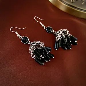 Vintage ethnic crystal tassel earrings with black beads on a red velvet background