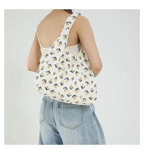 Detail of white canvas tote bag with yellow tulip floral print worn by a model