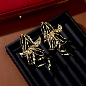 Detailed macro view of gold lily flower earrings with elegant wavy metal tassels
