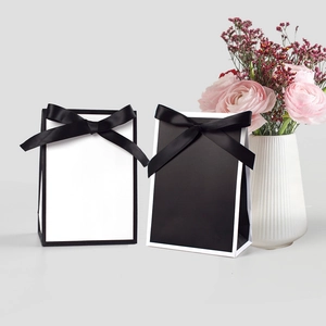 Minimalist black and white gift bags with elegant ribbon bows for wedding favors