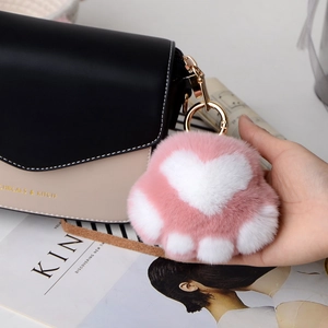 Detailed close-up of a pink and white plush cat paw keychain with gold metal clasp