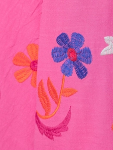 Macro detail of intricate floral embroidery on rose pink fabric with textured stitching