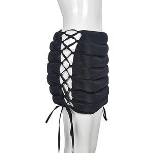 Detail view of black quilted mini skirt featuring side cross lace-up ties and glossy finish