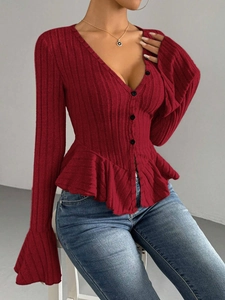 Close-up of red ribbed knit top featuring V-neck buttons and elegant peplum hem detail