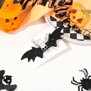 Halloween hair clip featuring black bat wings and skull detail on festive pumpkin background