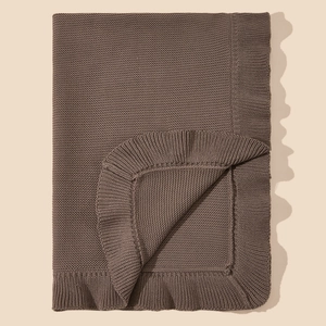 Detail of soft brown cotton knitted baby blanket with delicate ripple edges and texture