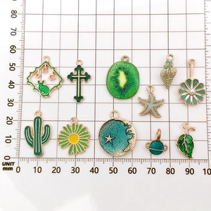 Green enamel fruit and flower charms set for DIY jewelry making on scale mat