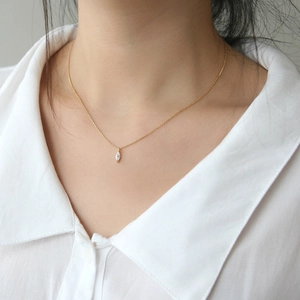 Close-up of a gold S925 silver necklace with a marquise-cut zircon on a model
