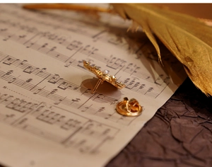 Close-up of golden floral brooch with pearls and rhinestones on vintage sheet music