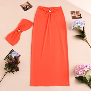 Detailed flat lay of orange maxi skirt set with matching headband and floral accents