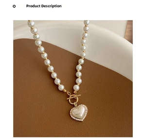Close-up of pearl necklace featuring heart pendant with zircon border and golden OT buckle