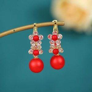 Detailed view of vintage gold flower earrings with red beads and sparkling rhinestones