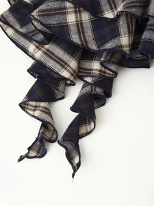 Macro detail of navy blue plaid fabric featuring ruffle hem and intricate stitching