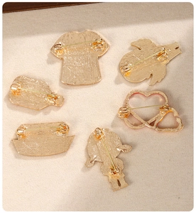 Detailed back view of medical brooches showing gold alloy finish and secure pin butterfly clutch