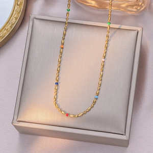Elegant rainbow bead and gold titanium steel necklace on champagne jewelry pad