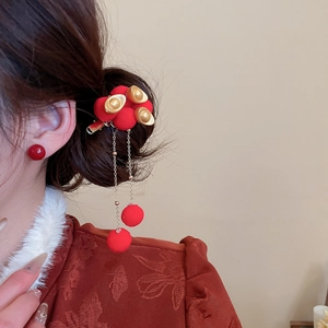 Detail showing plush pom-poms and gold sycee on tassel hair clip for festive styling