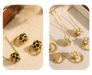 Détail de pendentifs cylindriques dorés avec gemmes vertes, zircons et perles blanches