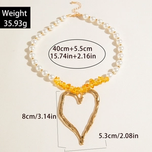 Detail of layered necklace with faux pearls, yellow stones, and large heart pendant