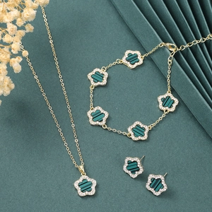 Detail of gold clover jewelry set with green striped inlay and sparkling crystal edges
