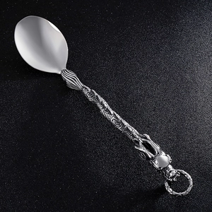 Detail of a silver stainless steel spoon with an intricately carved dragon handle