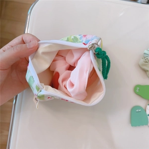 Close-up of small floral cotton storage pouch with green rope zipper and interior space