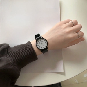 Minimalist quartz watch with black leather strap and white dial on an art magazine