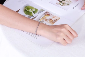 Detailed view of silver titanium steel chain bracelet on wrist over a fashion magazine