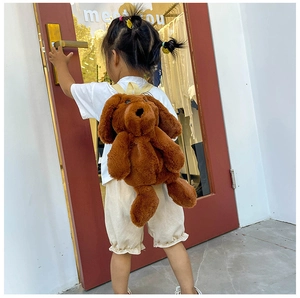 Detail view of dark brown plush dog backpack with soft fur on child model outdoors