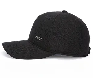 Detail view of the black textured baseball cap with a silver FASHION metal plaque