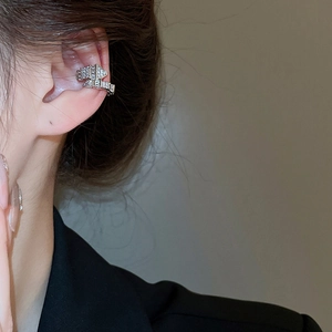 Detailed view of a silver snake-shaped zircon ear cuff on model with sparkling rhinestones