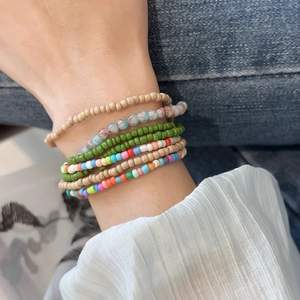 Detail of bohemian stackable beaded bracelets in mixed colors on a wrist wearing denim