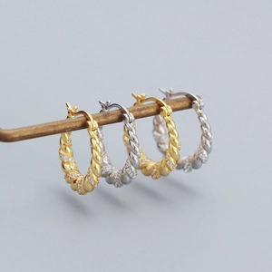 Macro detail of twisted silver hoop earrings with pave-set cubic zirconia crystals