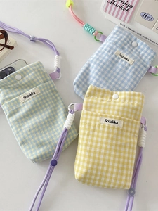 Three plaid fabric mini phone bags in blue, yellow, and green with purple drawstrings