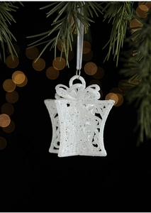 Close-up of a white glitter gift box ornament hanging on a green Christmas tree branch