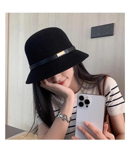 Dettaglio di un cappello pescatore nero in maglia con elegante fibbia dorata sul nastro