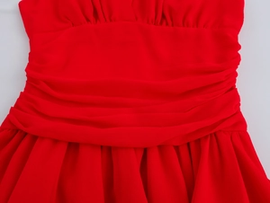 Detail of red sleeveless dress featuring a ruched waist and pleated chiffon fabric