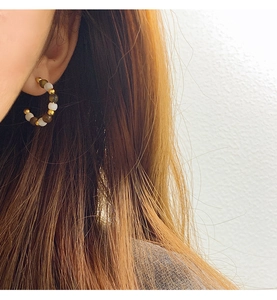 Detailed view of beaded C-shaped hoop earrings with brown tiger eye beads on model