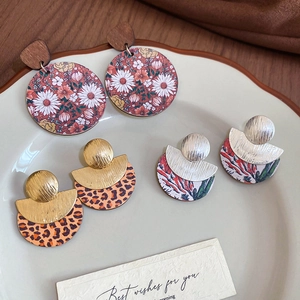 Détail de boucles d'oreilles vintage en bois avec motifs floraux et léopard sur platine