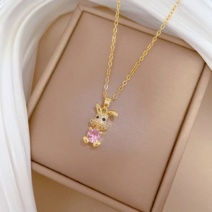 Macro shot of gold rabbit pendant with pink stone and white crystals in luxury jewelry box