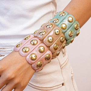 Stacked acrylic chunky bracelets with marble texture and gold studs on wrist