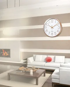 Close-up of a silent wall clock with rose gold frame and white dial in a modern living room
