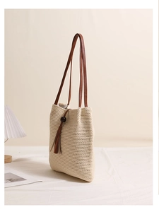 Detail of woven beige cotton shoulder bag with brown tassel and thick textured strap