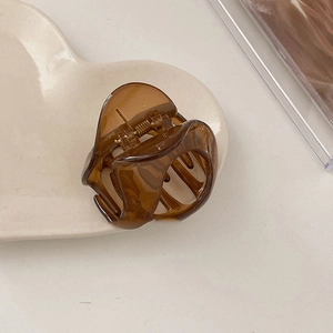 Elegant amber acrylic hair claw clip displayed on a white heart-shaped ceramic plate